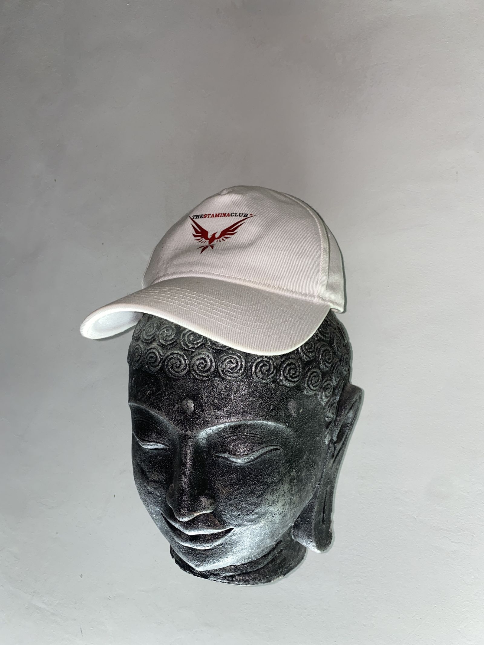 Branded cap resting on a Buddha head ornament