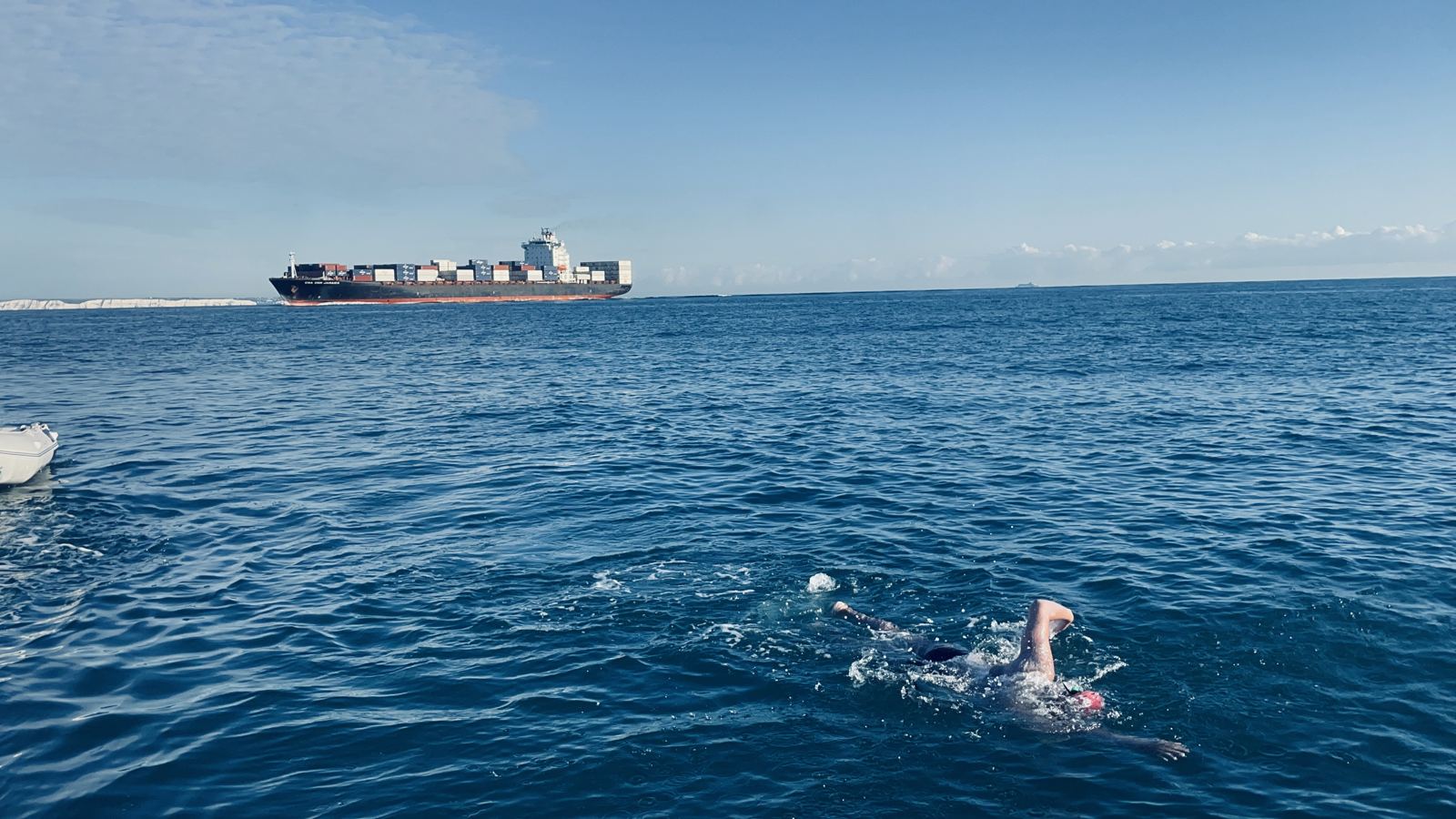 Open water swim past a container ship