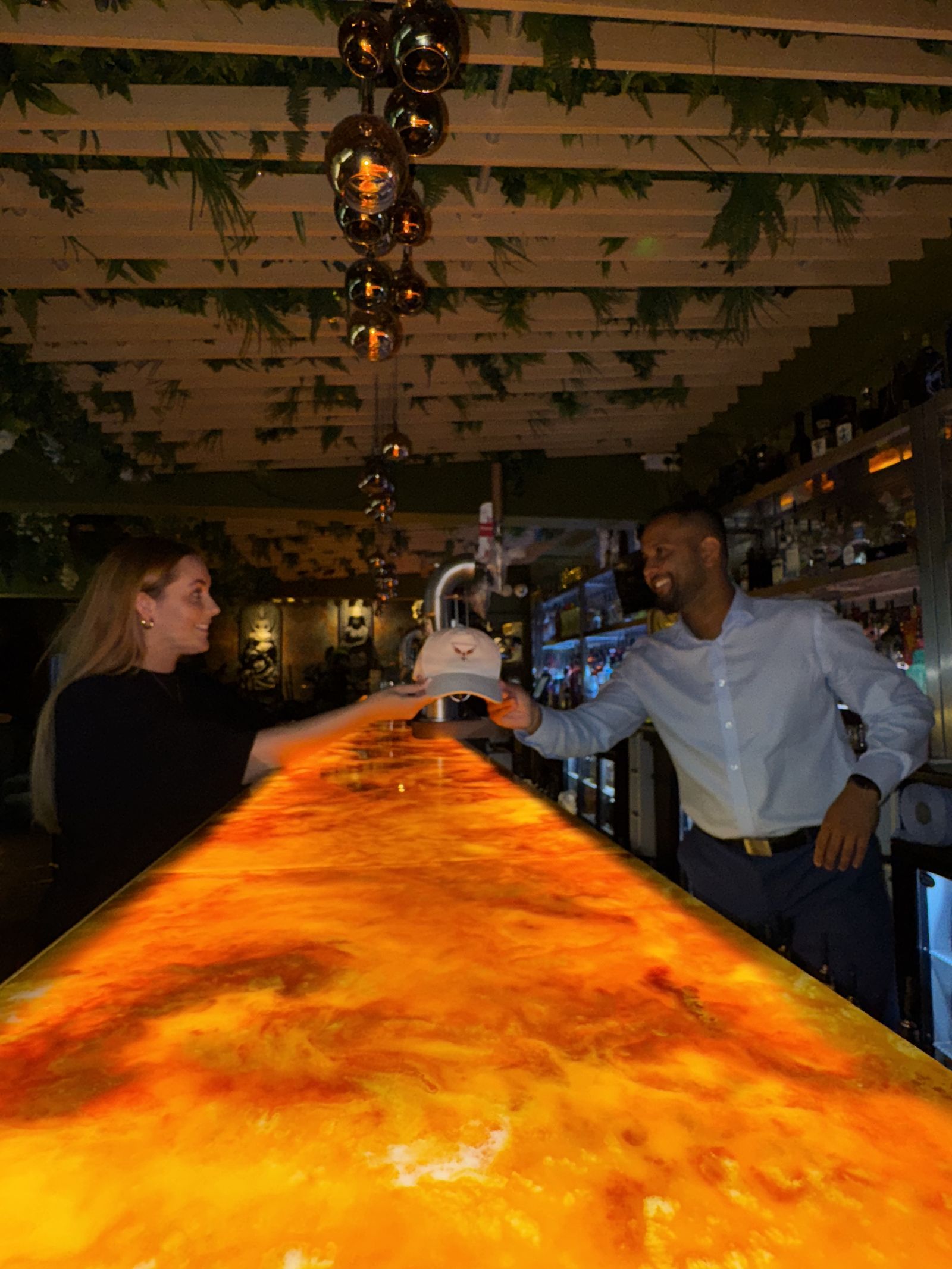 Handing over a branded cap at a bar